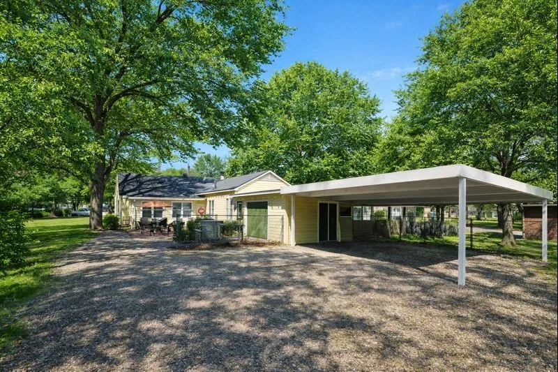 Large lot with attached garage, carport, and outdoor cooking area.