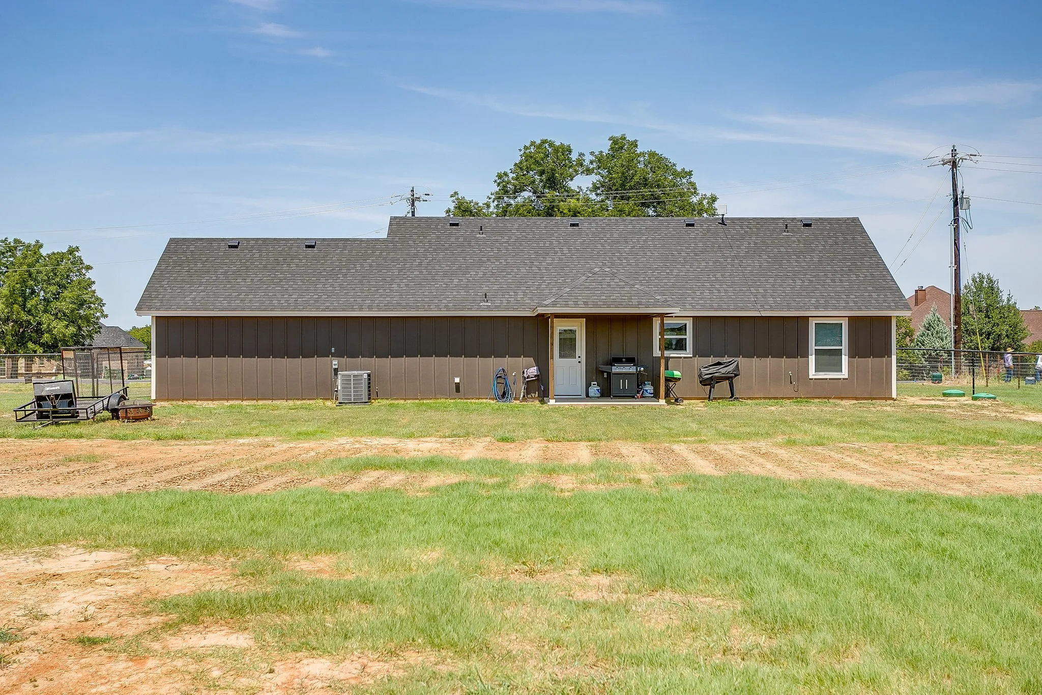 Exterior featuring dark siding, a dark shingle roof, and a covered back patio