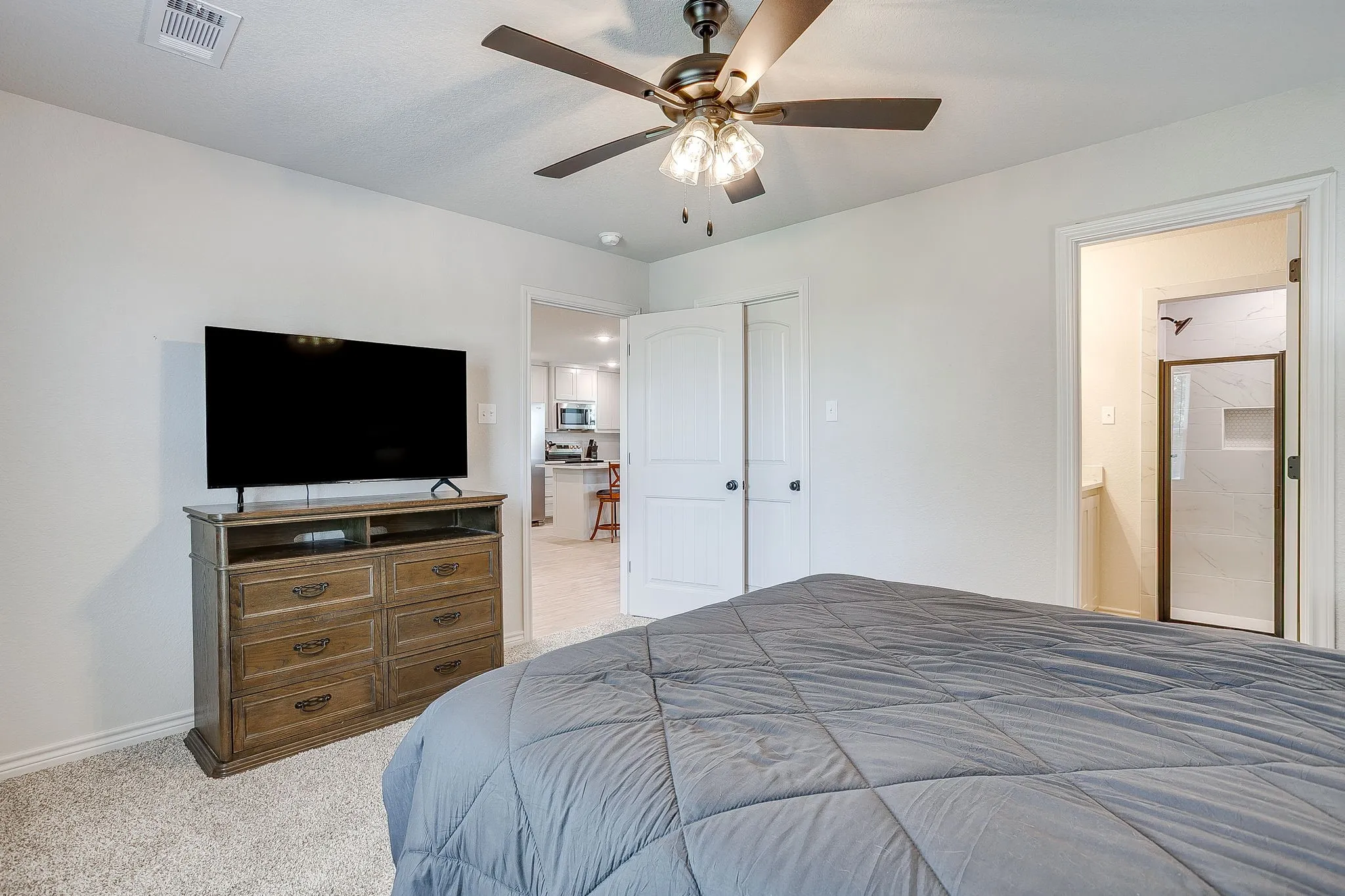 Plush carpet flooring, ceiling fan with integrated lighting, and a white interior door