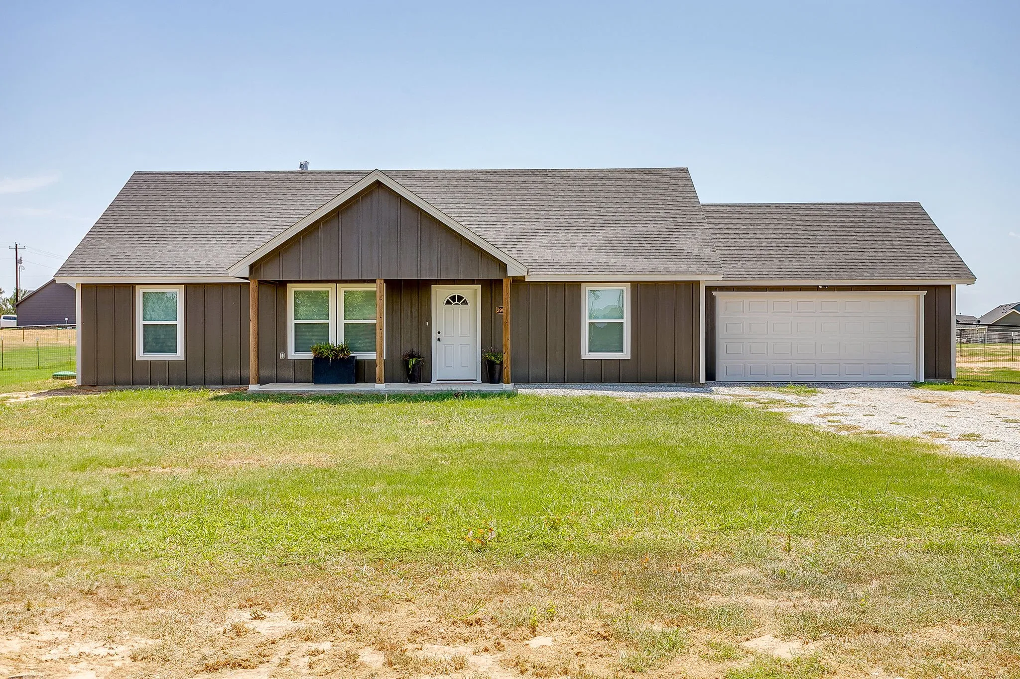 Single-story residence featuring vertical board siding, a covered front porch, and an attached two-car garage