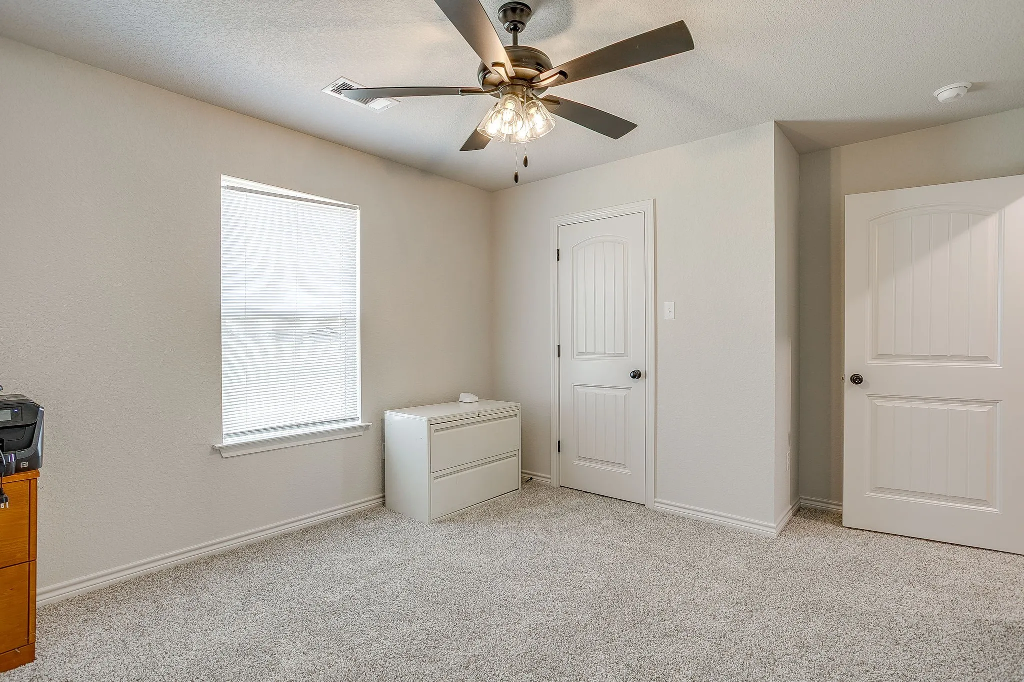 Wall-to-wall carpeting, window with blinds, ceiling fan with light fixture, and paneled doors