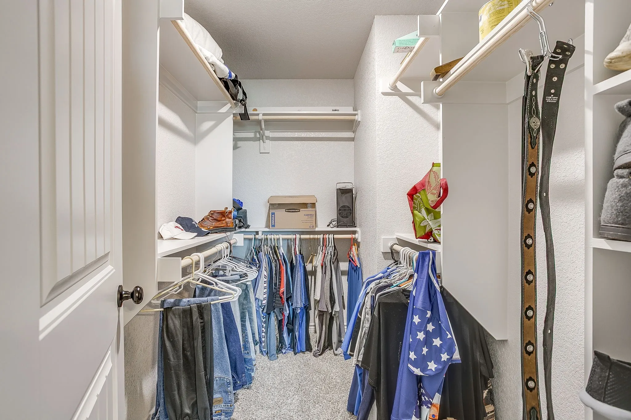 Walk-in closet with carpet flooring, white shelving, and multiple clothing rods