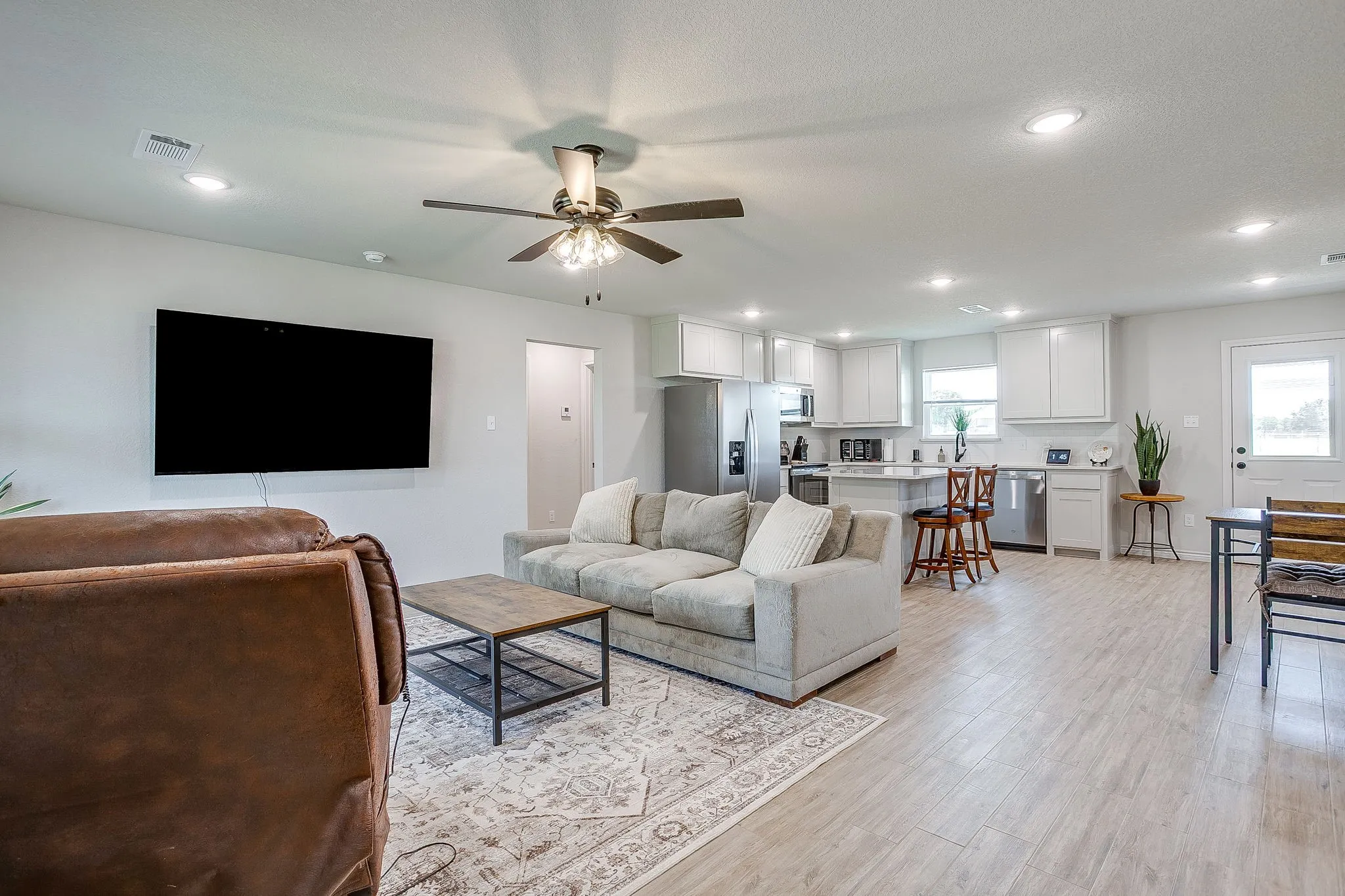 Open-concept living space featuring wood-finish flooring, recessed lighting, and a ceiling fan