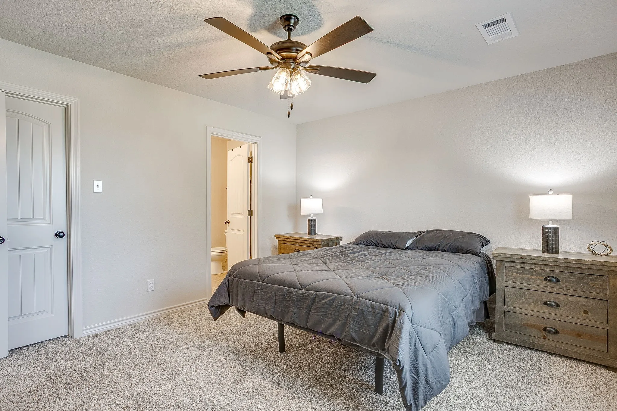 Carpeted bedroom with a ceiling fan, light-toned walls, and white panel doors