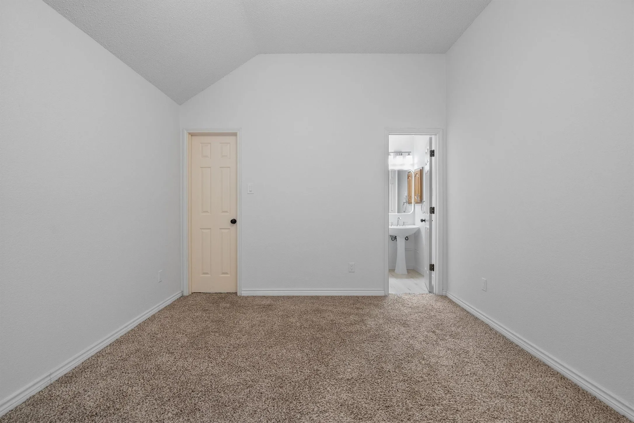 Carpeted room featuring a vaulted ceiling and white walls