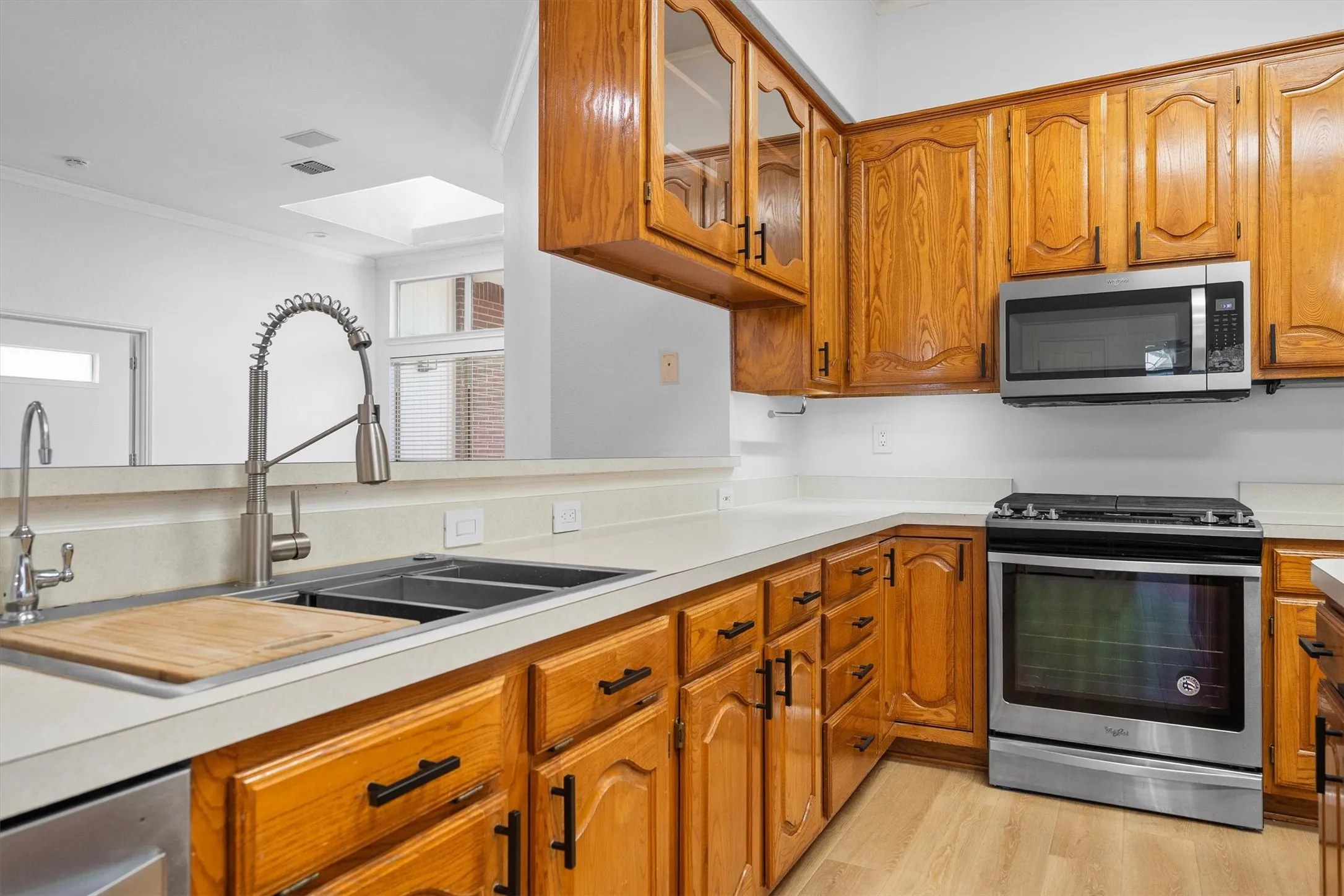 Kitchen featuring wood-finish cabinetry with black hardware, light-toned countertops, and wood-finish flooring