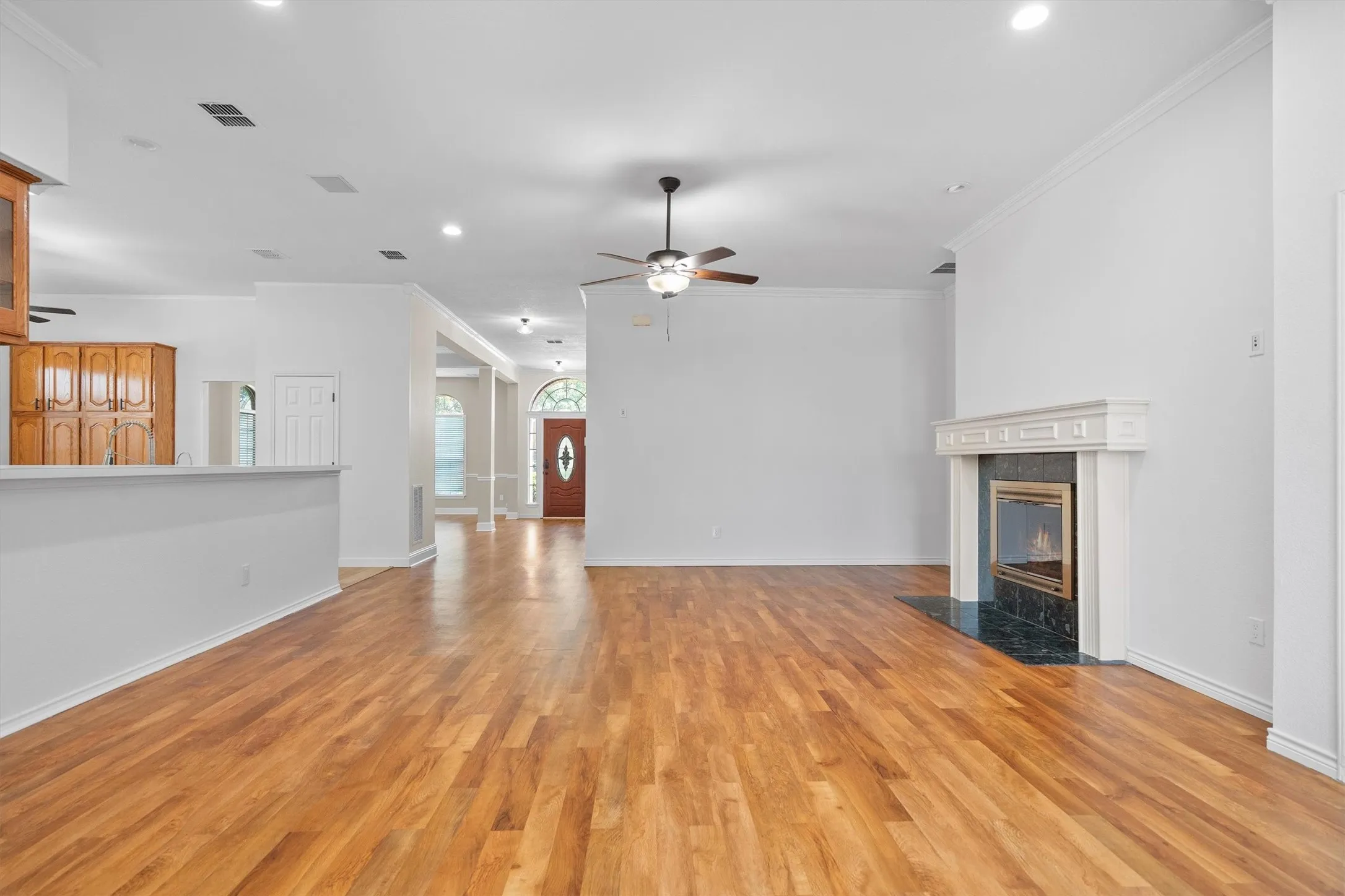 Spacious interior featuring wood-finish flooring, a decorative fireplace with a dark stone hearth and surround, and a ceiling fan