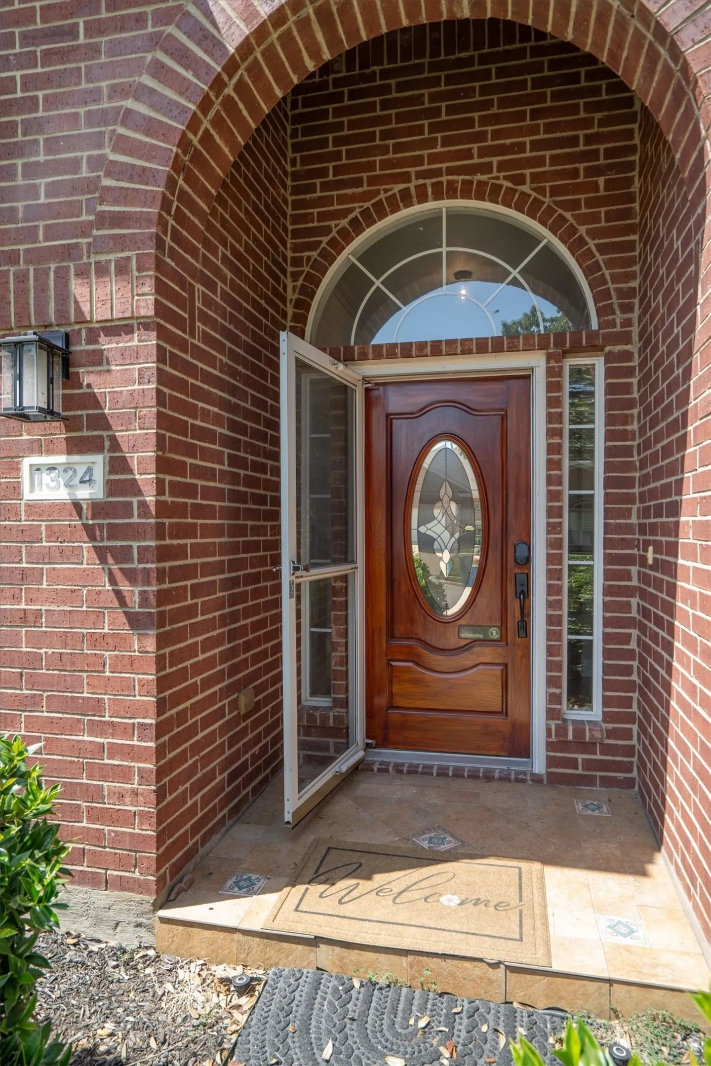 Brick facade featuring an arched entryway with a solid wood front door