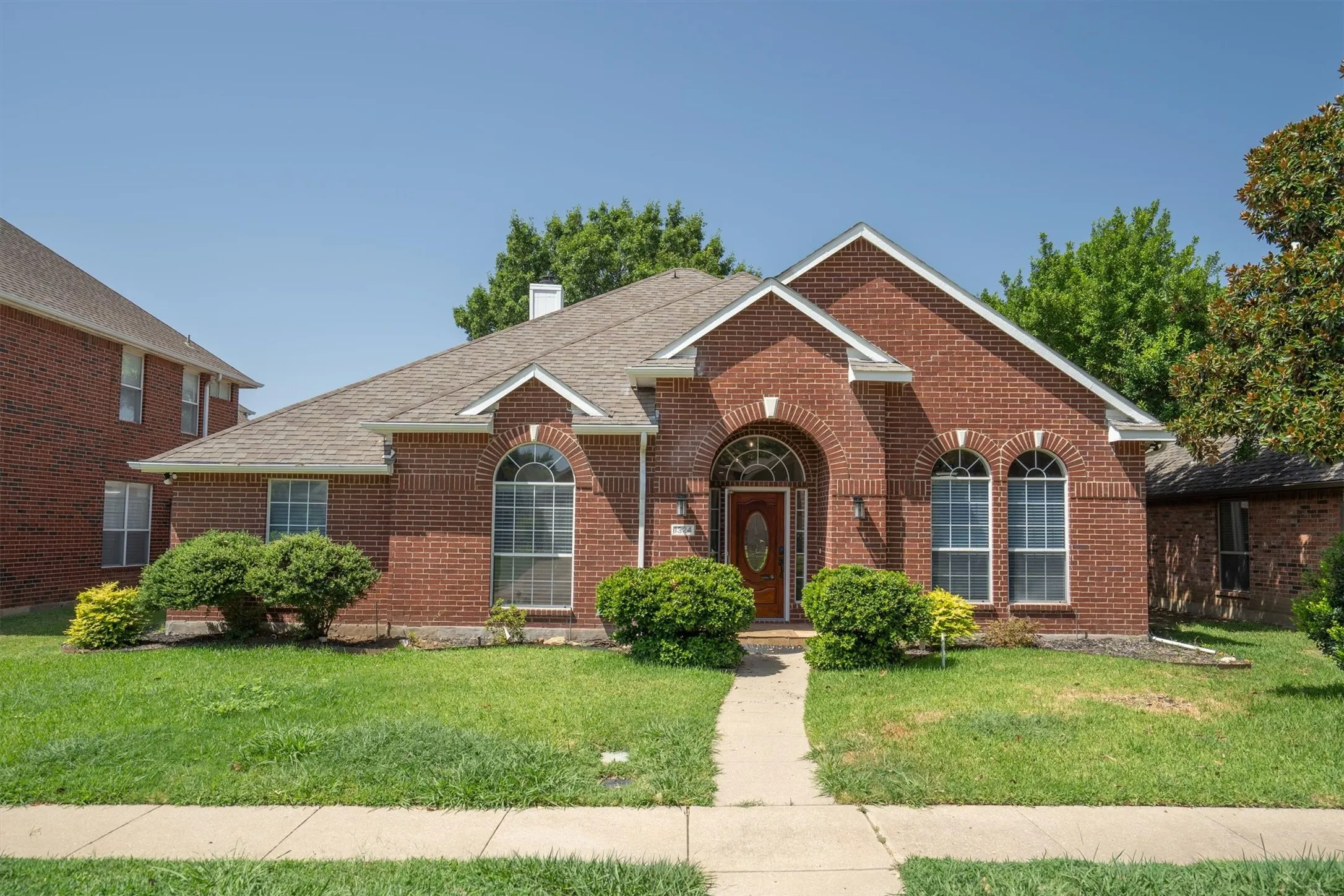 Brick facade residence featuring arched entry and window details
