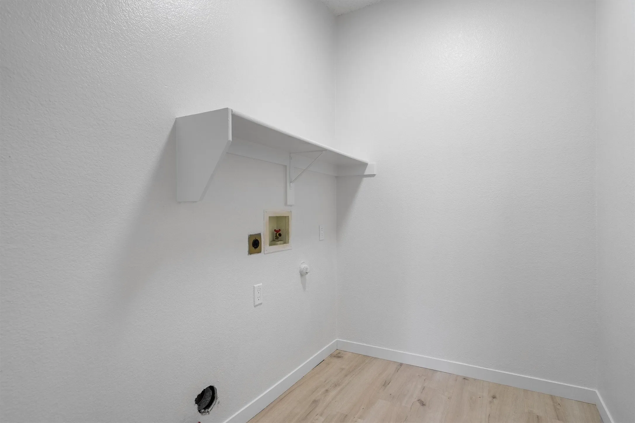Dedicated utility area featuring a built-in shelf, appliance hookups, and wood-finish flooring