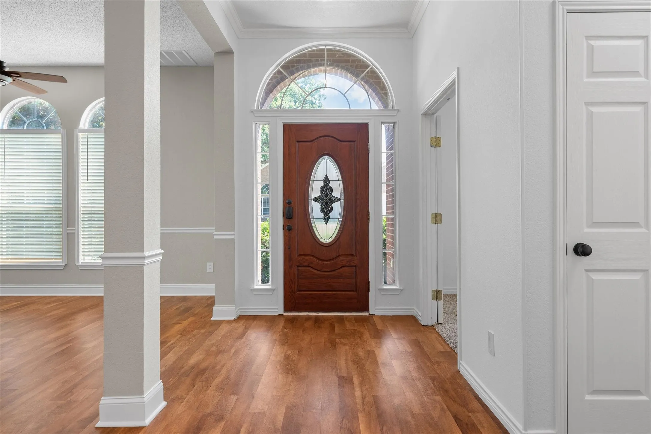Entryway featuring a wood-finish door with decorative glass, sidelights, and an arched transom window