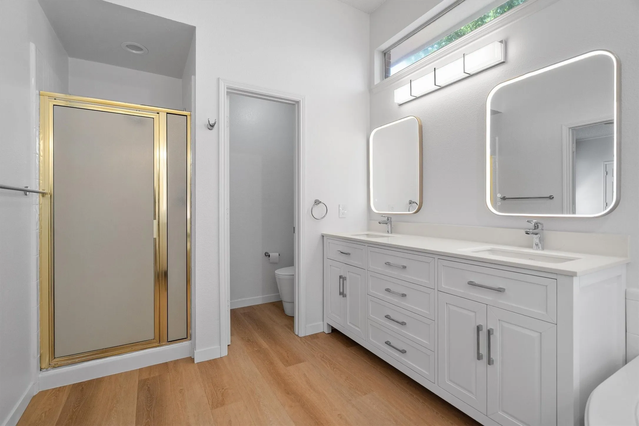 Contemporary bathroom featuring a double vanity with white cabinetry, integrated sinks, and chrome fixtures
