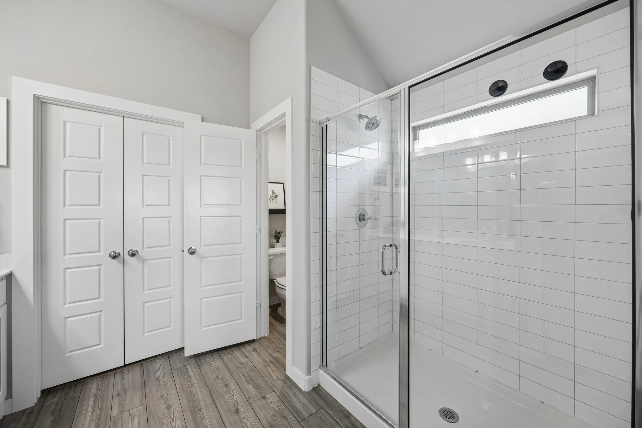 Modern walk-in shower with clear glass enclosure and white subway tile surround.