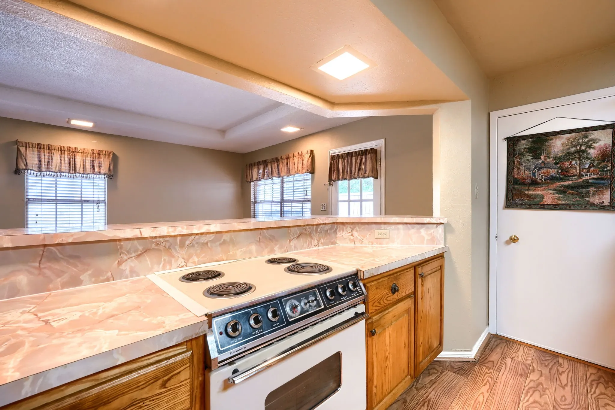 Kitchen featuring a built-in electric range, light-toned wood cabinetry, and a countertop with integrated backsplash