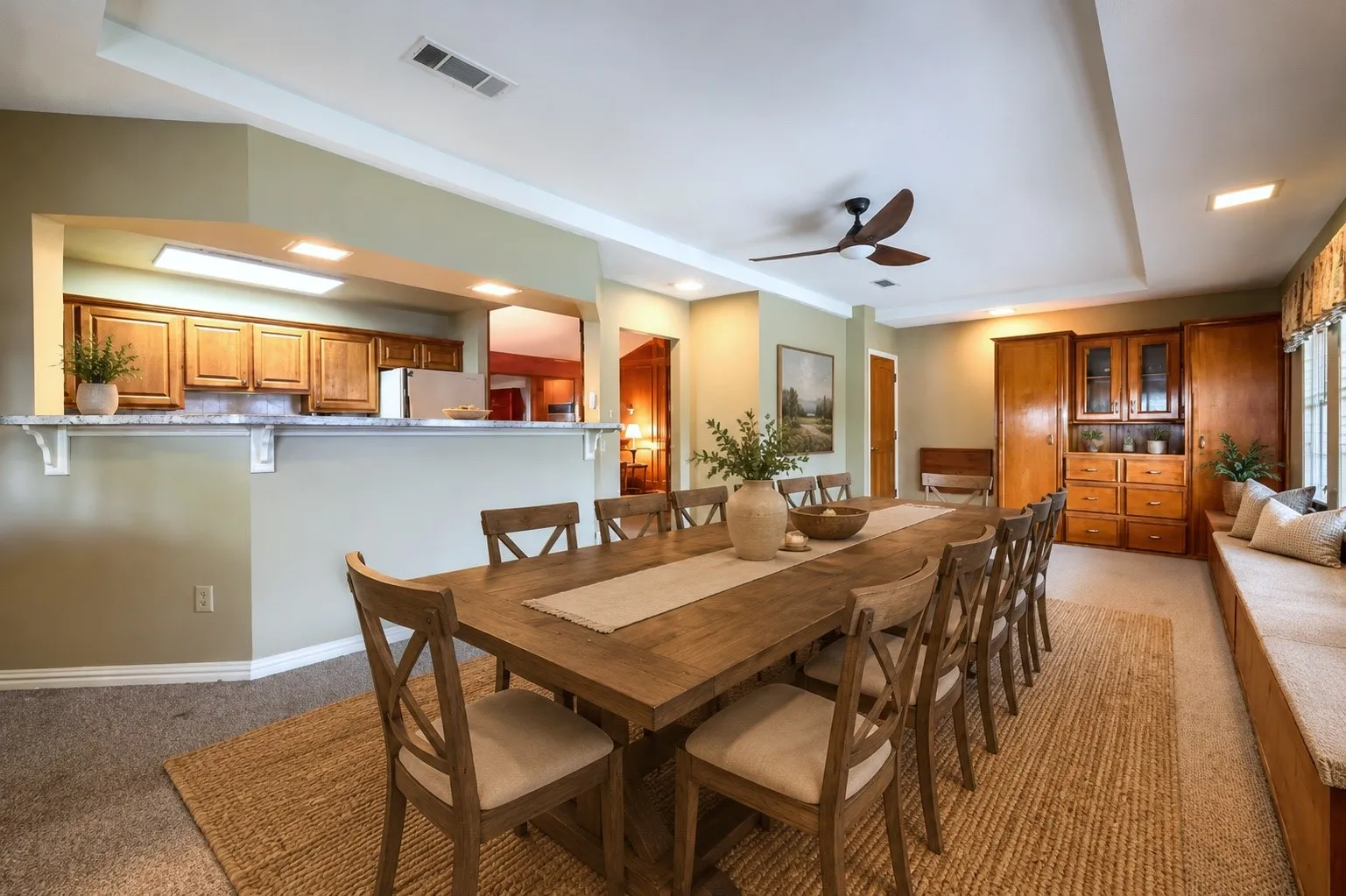 Spacious dining area featuring a tray ceiling with a ceiling fan, a built-in window bench, and wood-finish cabinetry- AI- Layout version 2