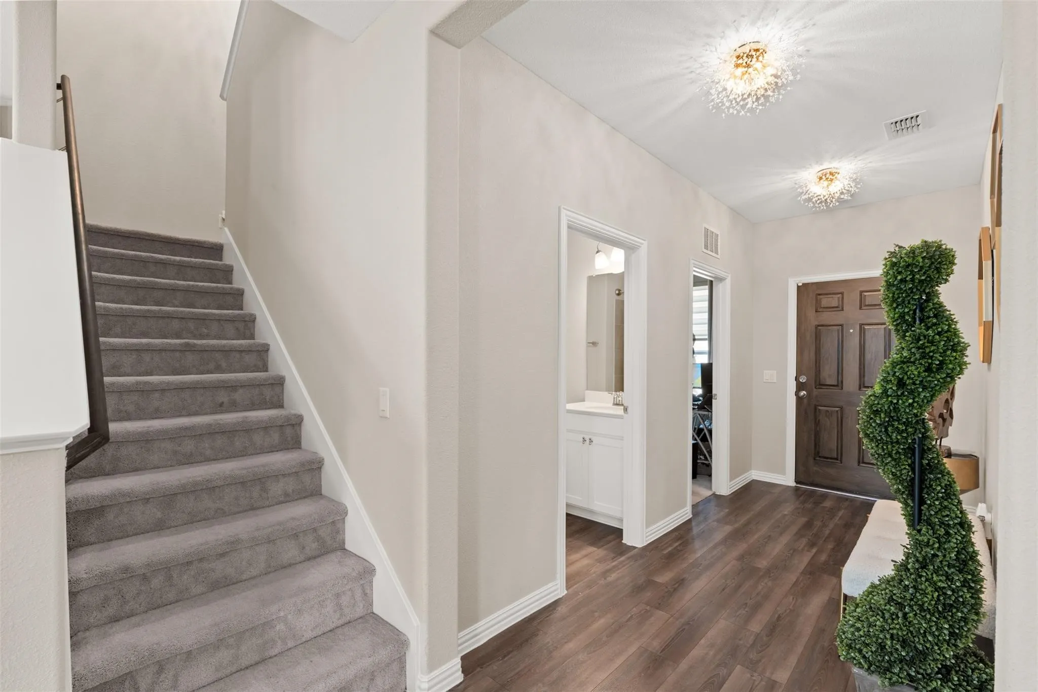 Entryway featuring wood-finish flooring, a paneled front door, and two decorative ceiling light fixtures