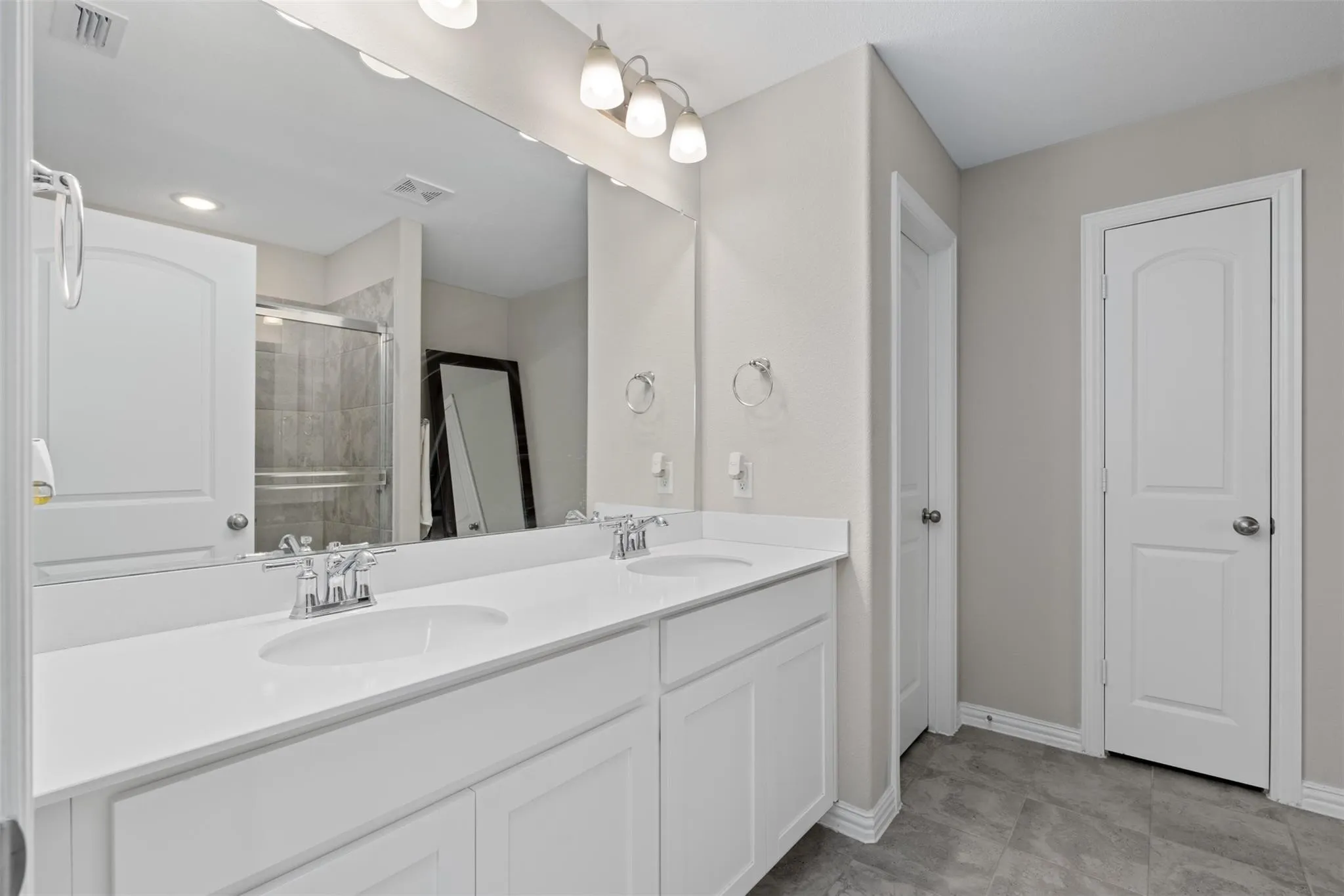 Dual sink vanity with white cabinetry, white countertops, and chrome fixtures