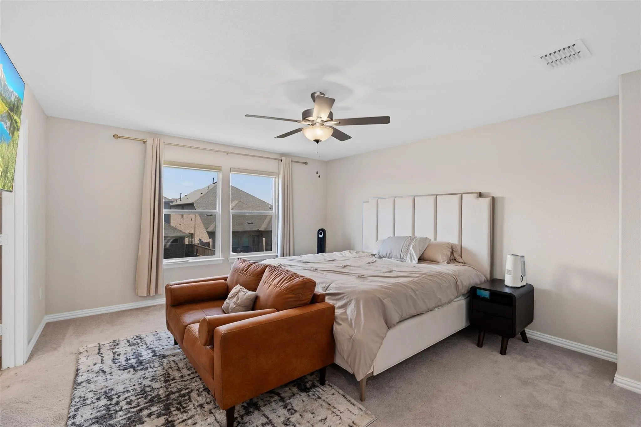 Carpeted room featuring dual windows, a ceiling fan with integrated lighting, and neutral wall tones