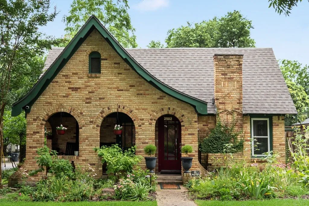 Brick facade residence featuring a prominent chimney and a dark green trim