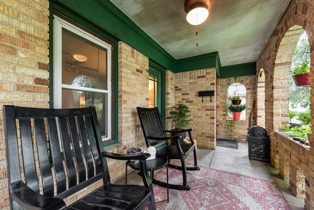 Brick-clad porch featuring arched openings, a ceiling-mounted light fixture, and a solid entry door with sidelight