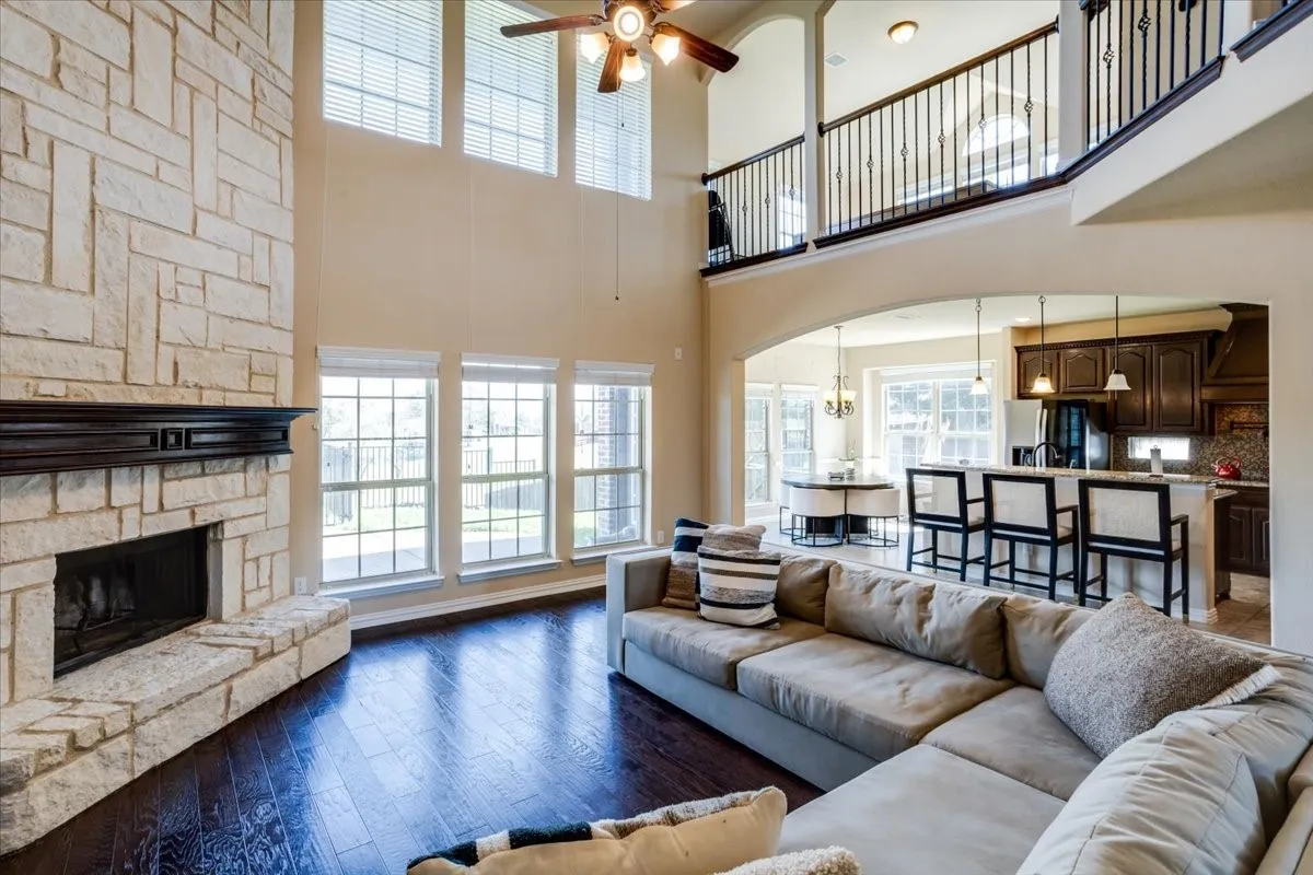 Living area featuring a ceiling fan, arched walkways, dark wood-style floors, a fireplace, and a high ceiling