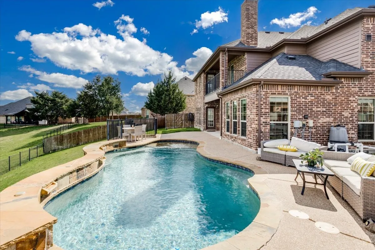 View of swimming pool with a balcony, a fenced backyard, patio surround, and an outdoor living / dining area