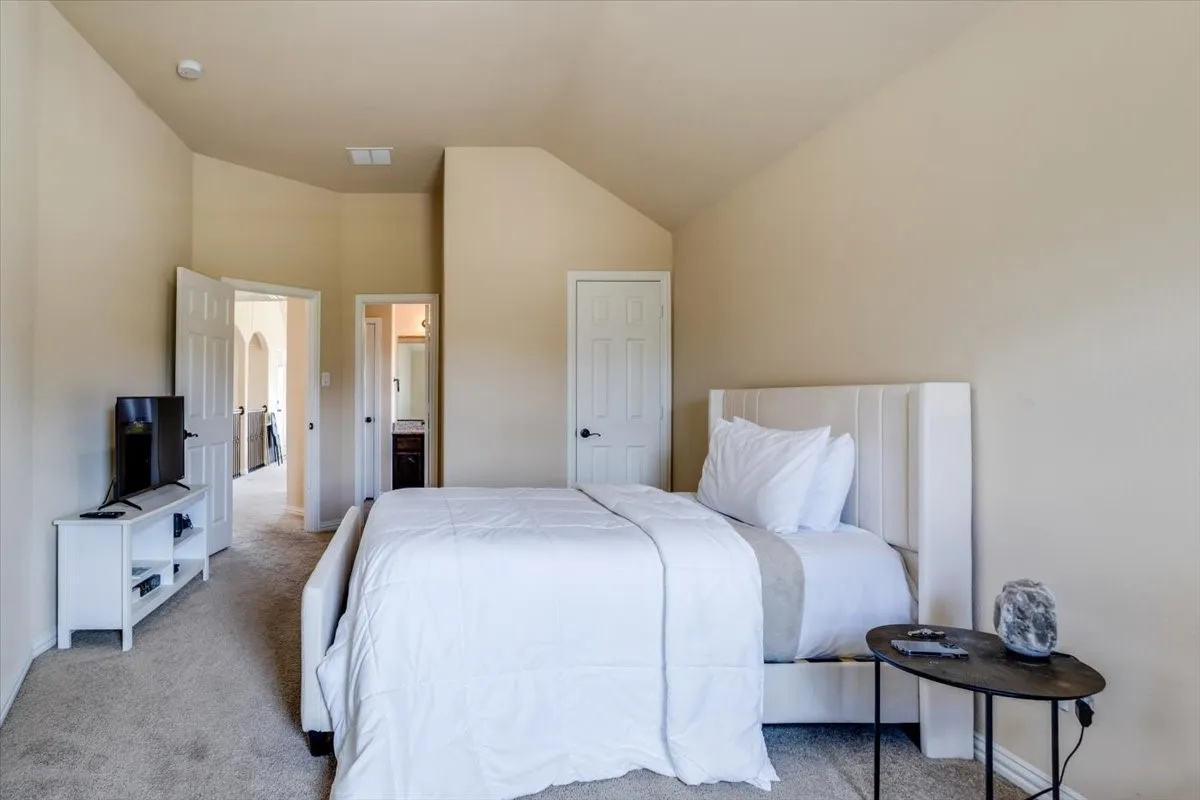 Bedroom featuring connected bathroom, carpet floors, and lofted ceiling