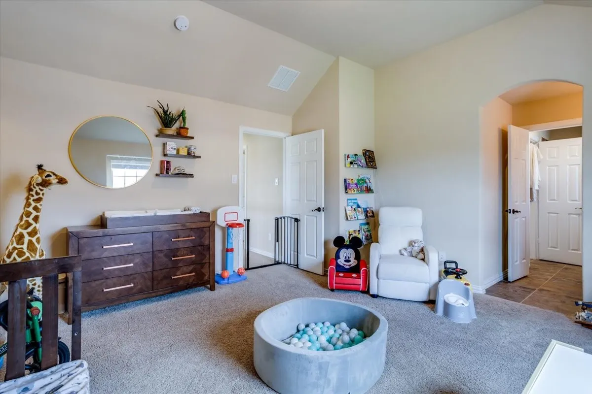 Bedroom with vaulted ceiling, carpet floors, and arched walkways