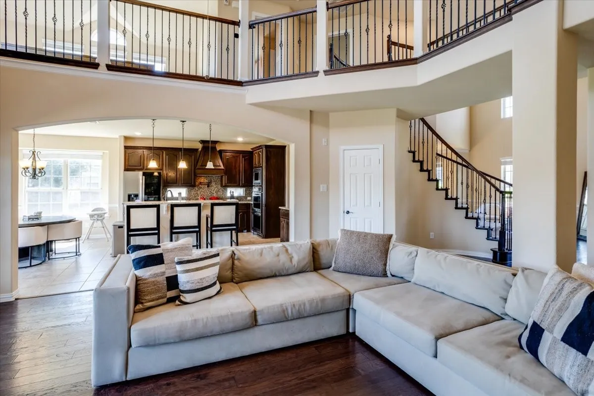 Living area featuring arched walkways, hardwood / wood-style floors, a high ceiling, and a chandelier