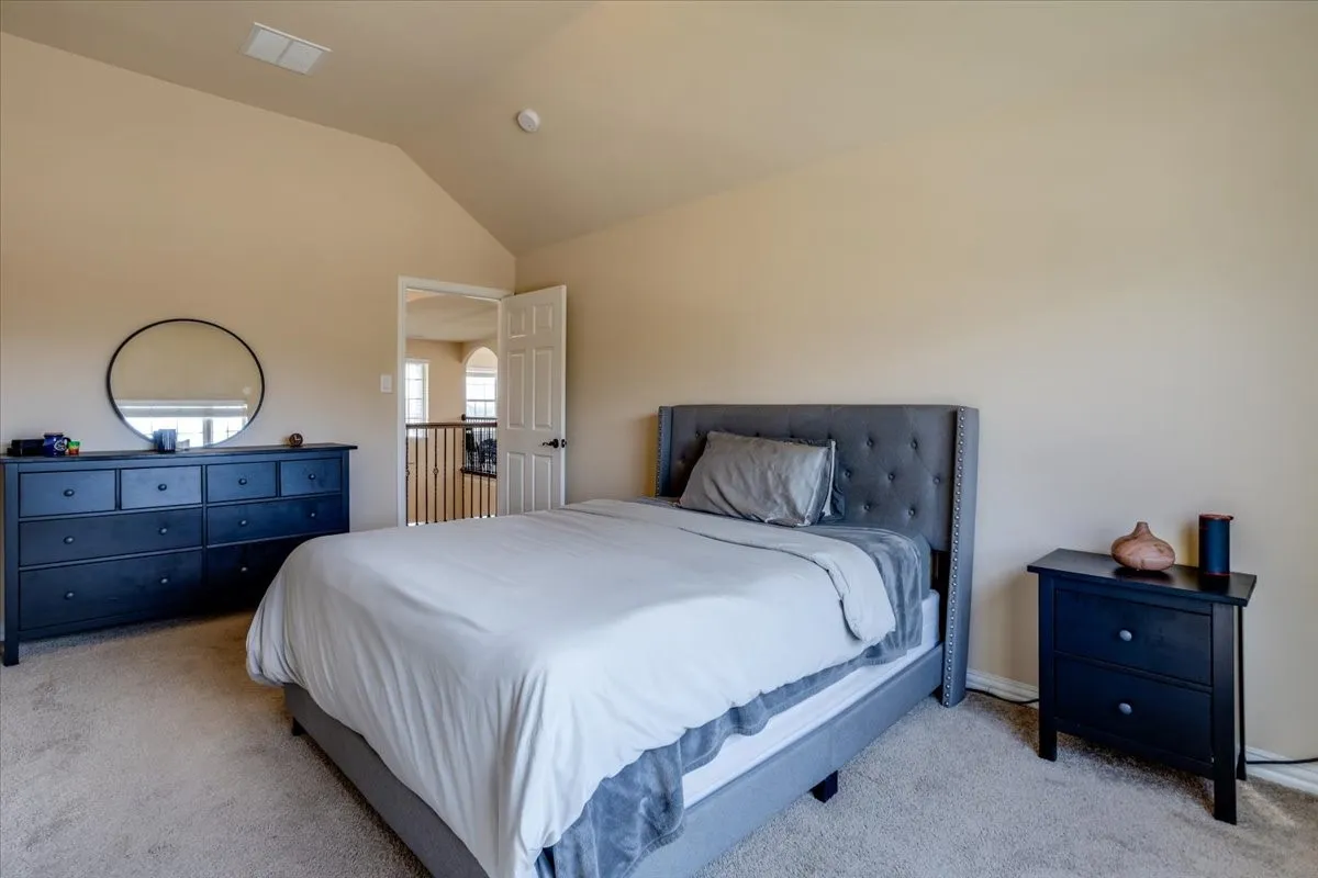 Bedroom with light carpet and lofted ceiling