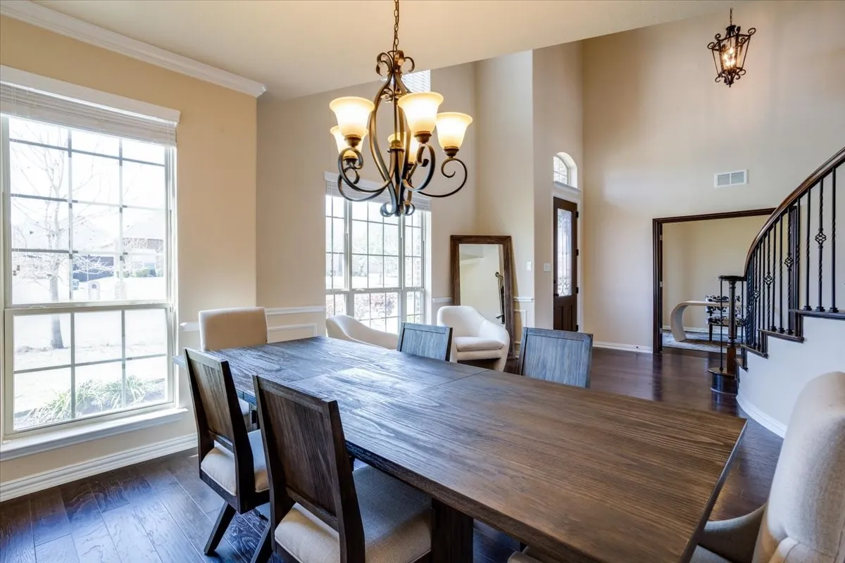 Dining room with dark wood-type flooring, suspended lighting, plenty of natural light, and ornamental molding