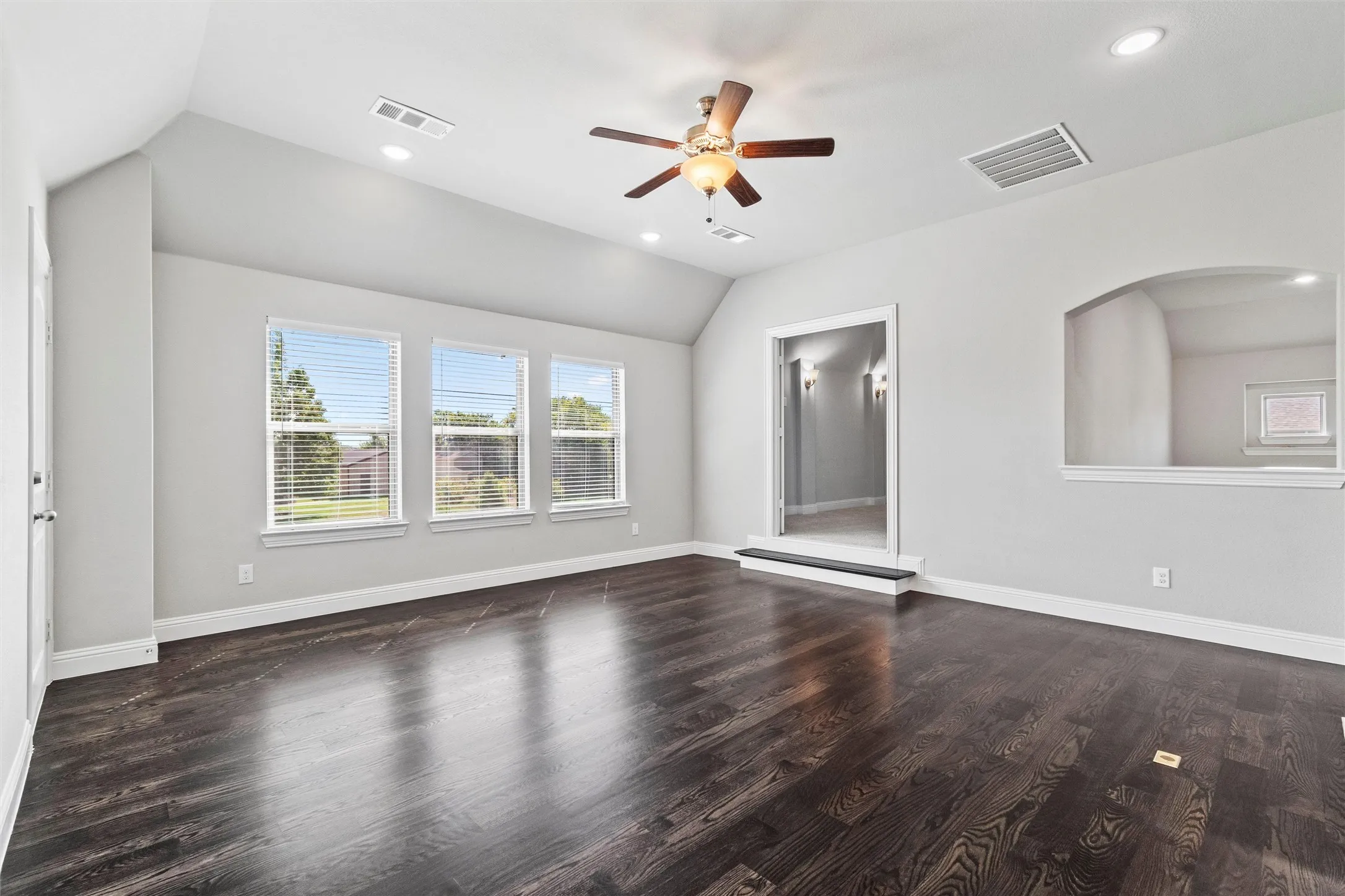 Unfurnished living room featuring hardwood / wood-style flooring, vaulted ceiling, and ceiling fan