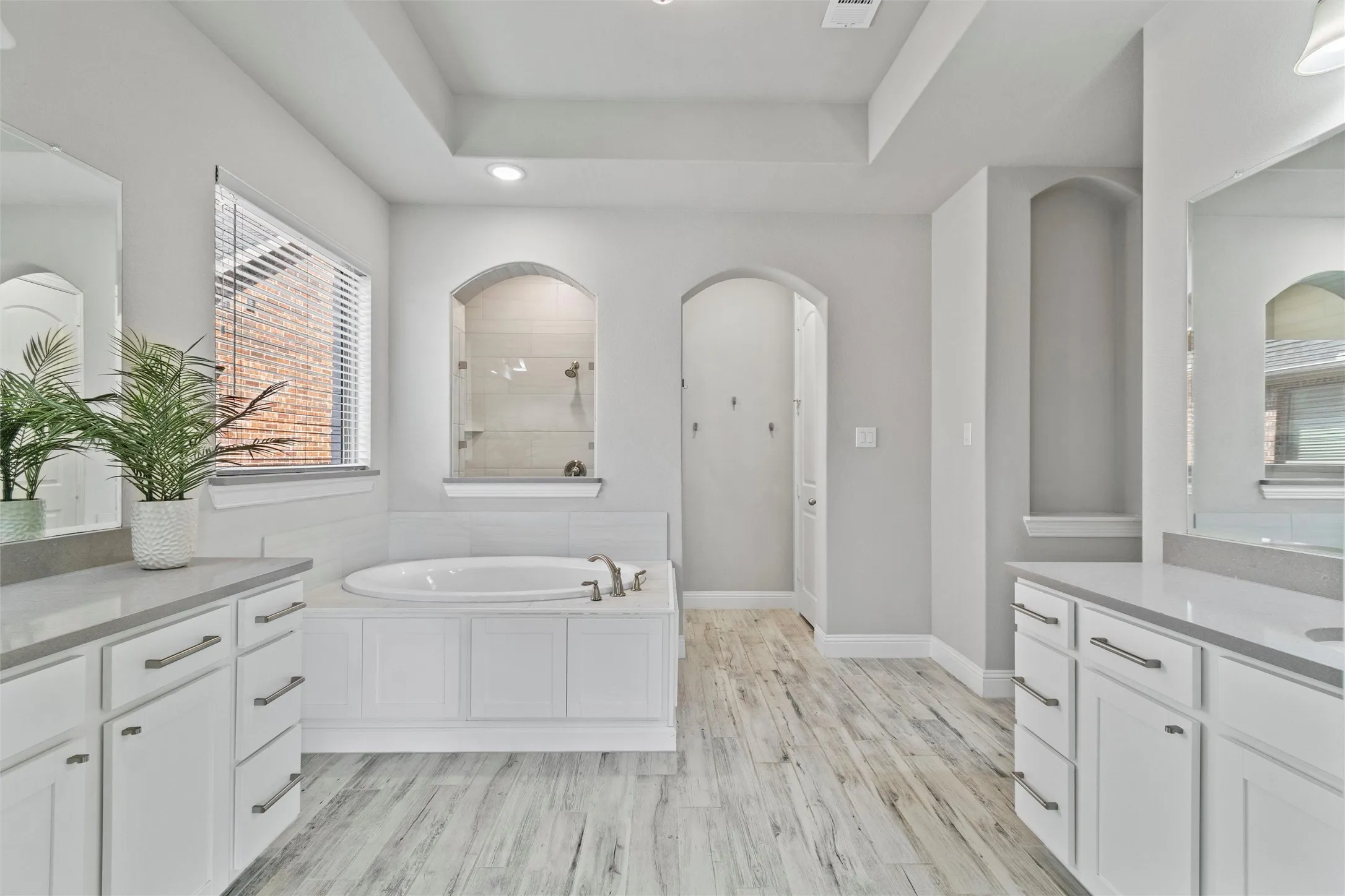 Bathroom featuring vanity, a raised ceiling, hardwood / wood-style floors, and a tub