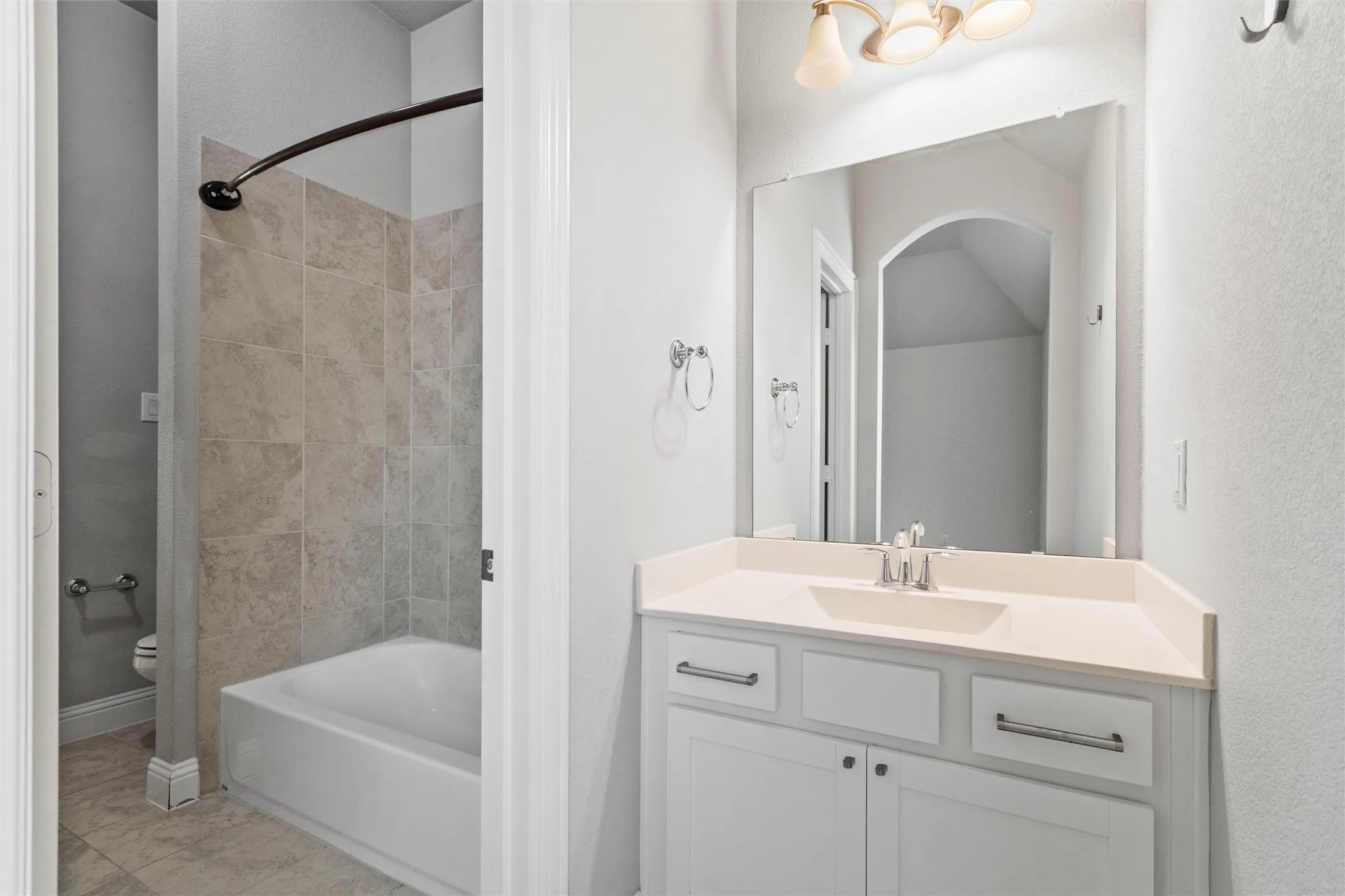 Full bathroom with tiled shower / bath combo, tile patterned floors, toilet, and vanity