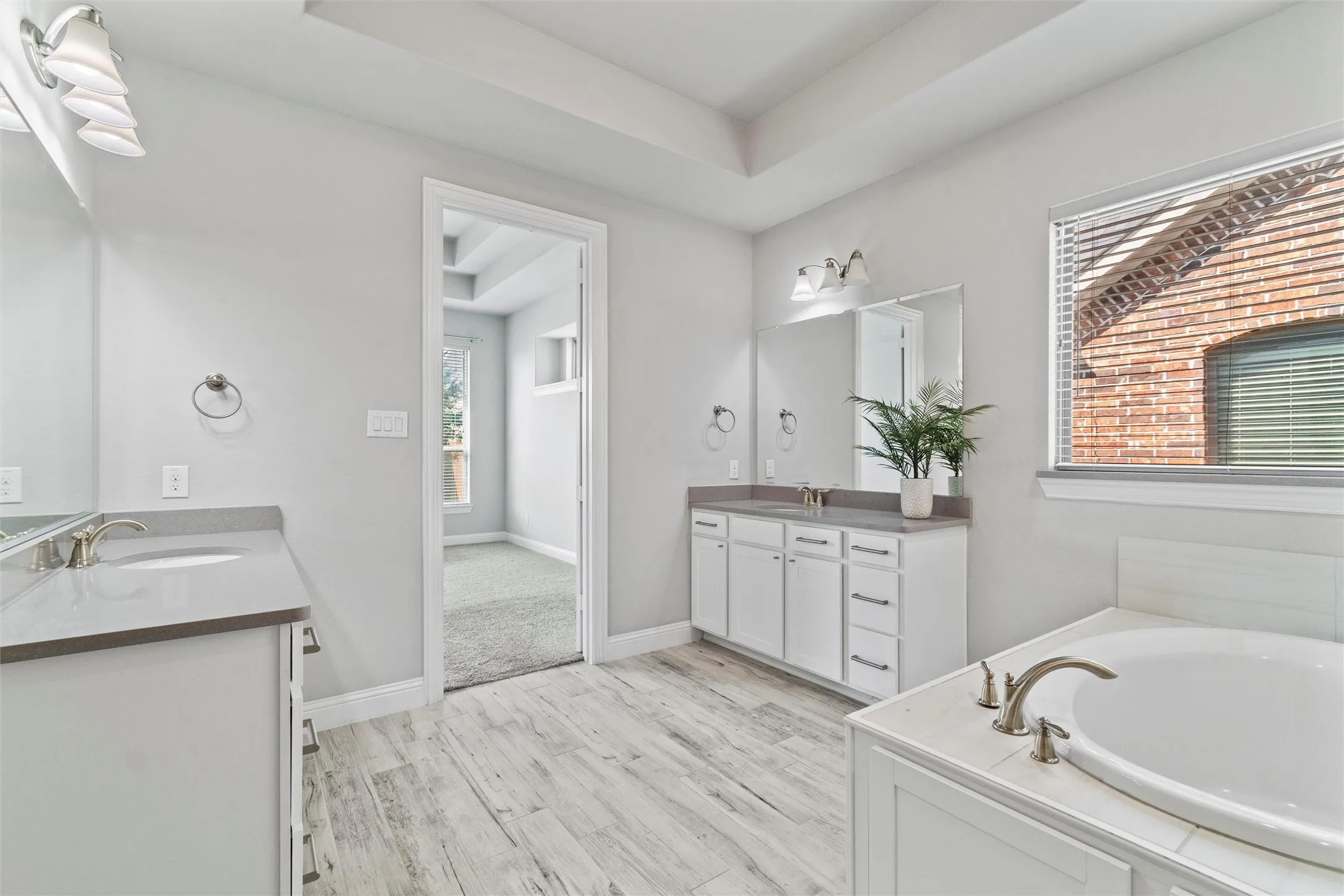 Bathroom featuring a washtub, wood-type flooring, dual vanity, and plenty of natural light