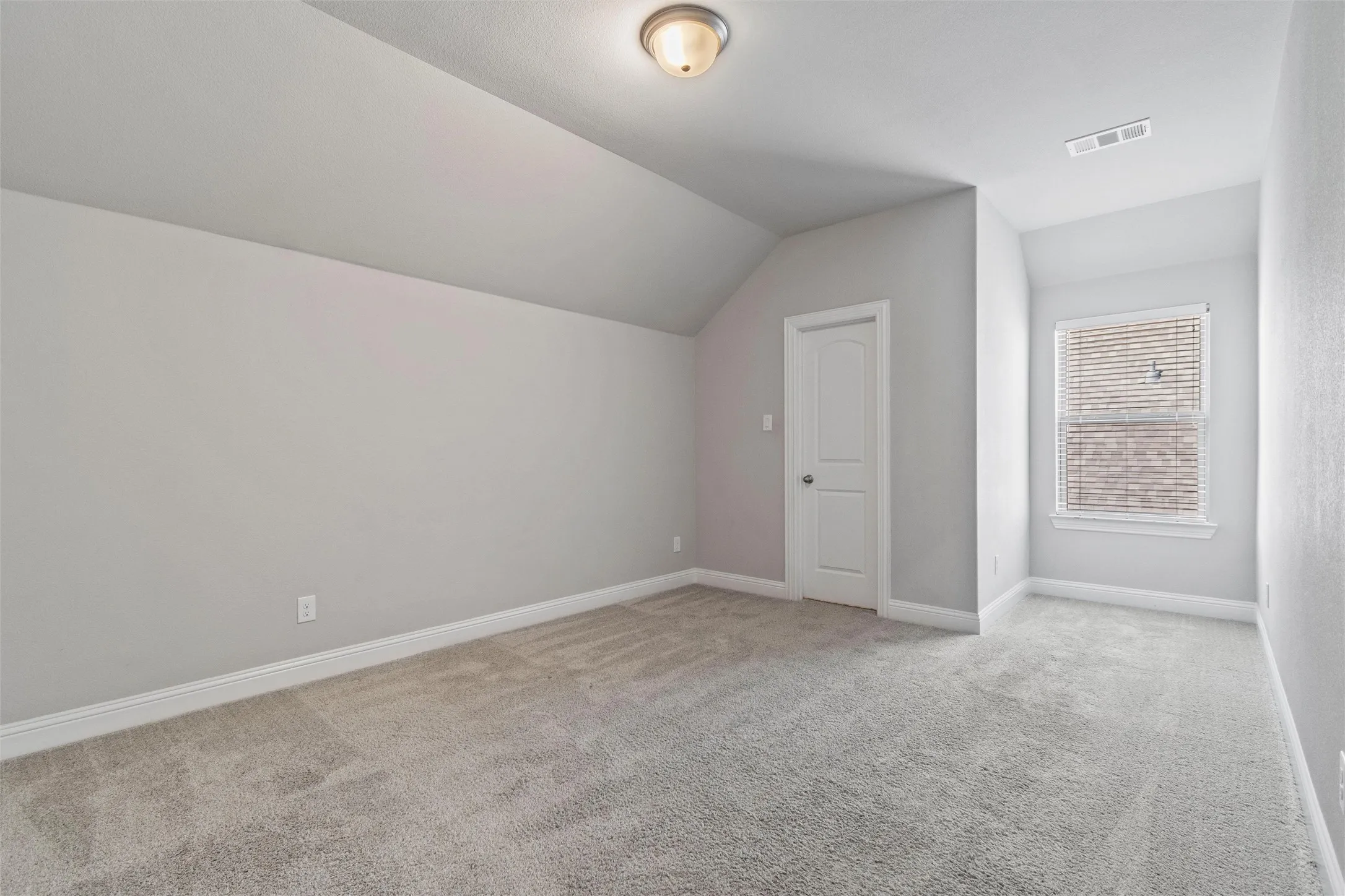 Additional living space featuring vaulted ceiling and light colored carpet