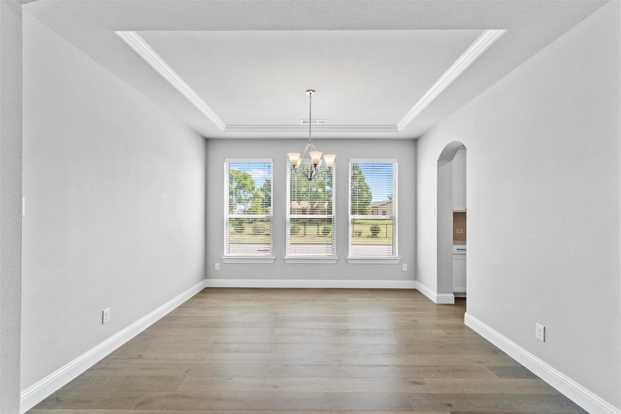 Unfurnished dining area with an inviting chandelier, hardwood / wood-style flooring, and a raised ceiling