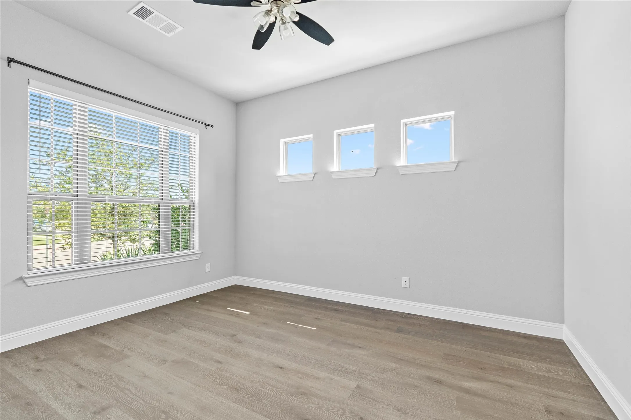 Unfurnished room with a wealth of natural light, ceiling fan, and hardwood / wood-style floors