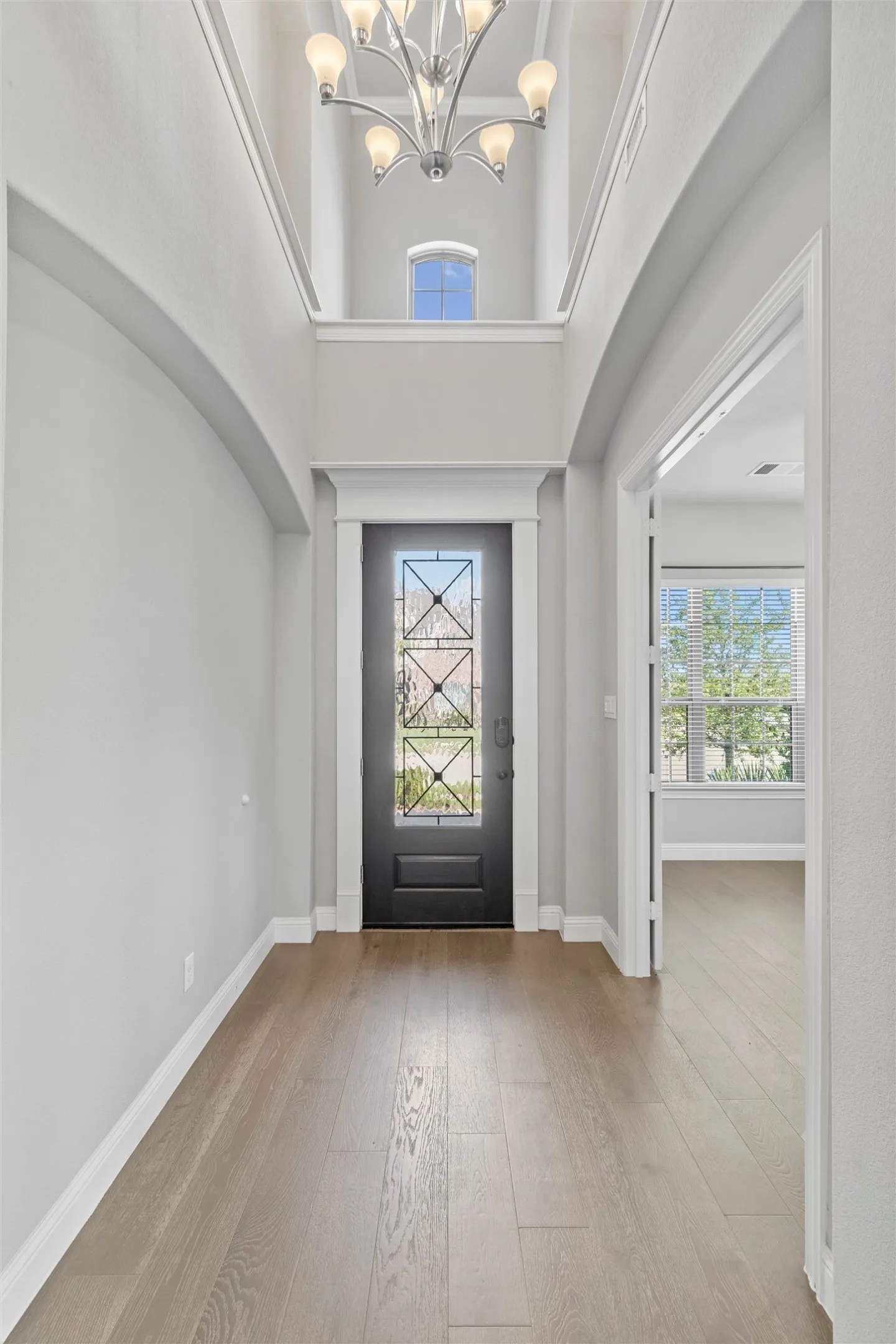 Foyer featuring a high ceiling, hardwood / wood-style flooring, and a notable chandelier