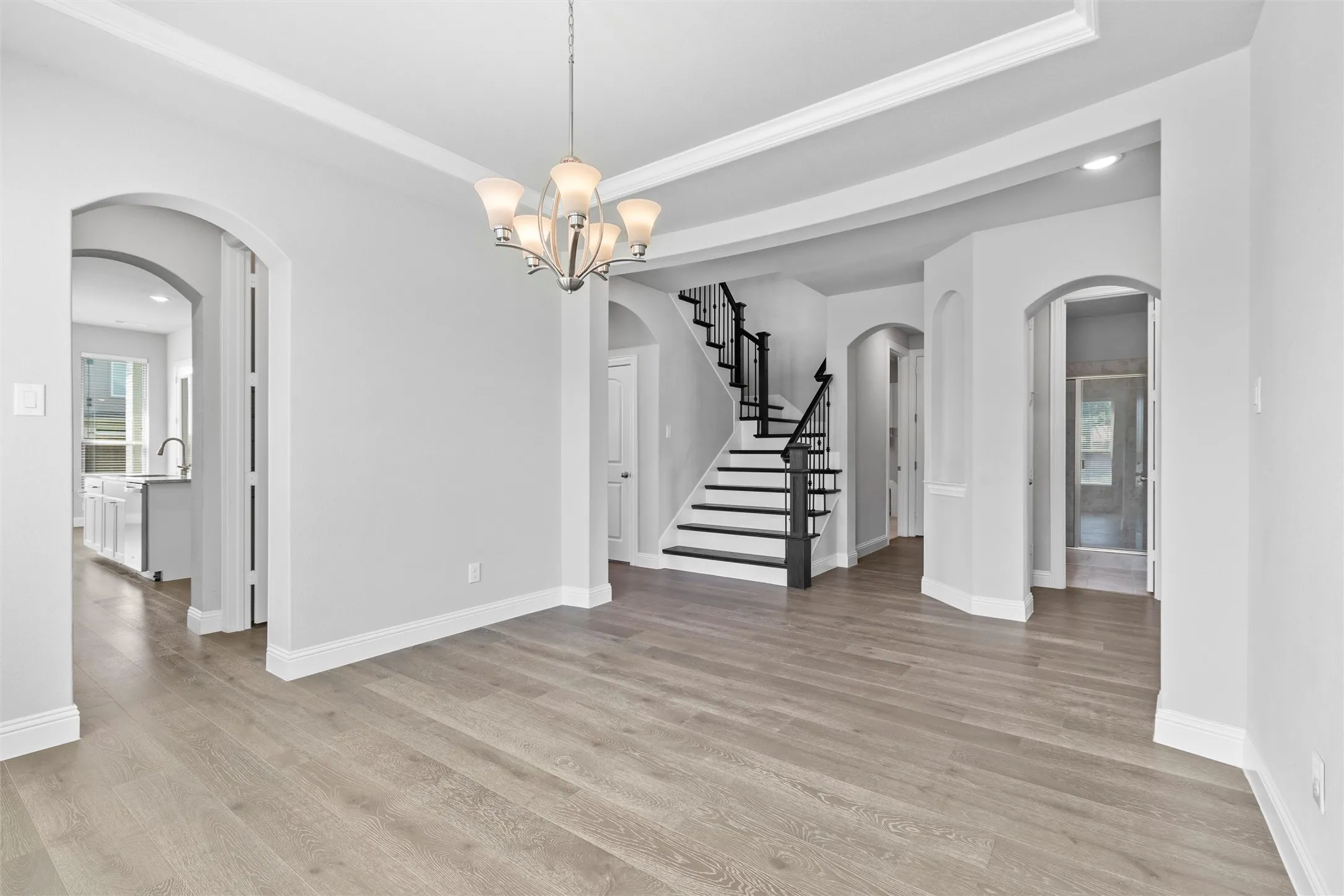 Spare room featuring a chandelier, a raised ceiling, and light hardwood / wood-style floors