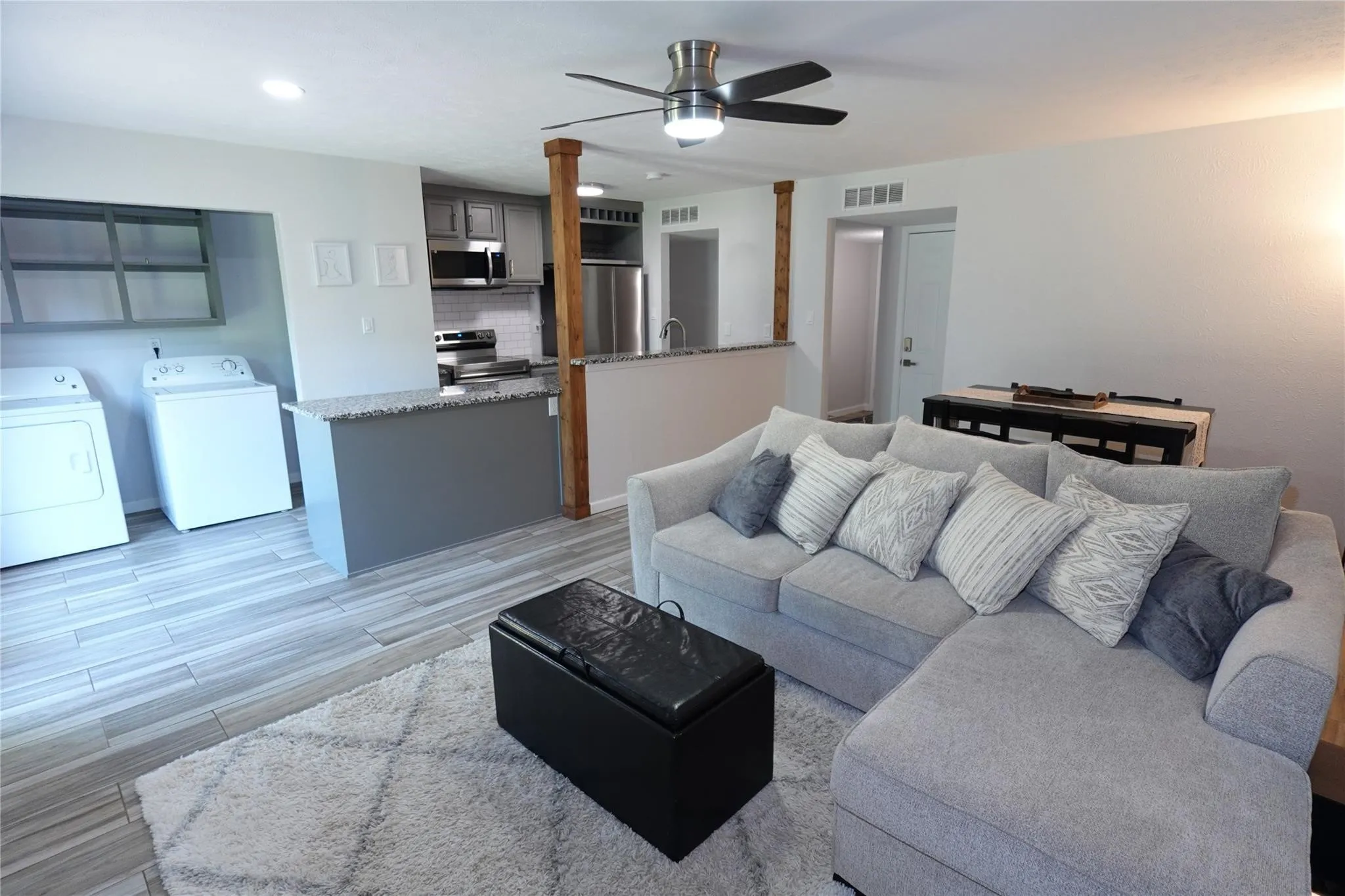 Open-concept living area featuring wood-finish flooring, a contemporary ceiling fan, and a kitchen with stainless steel appliances