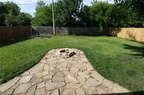 Expansive lawn featuring a flagstone patio with an integrated fire pit
