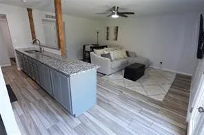 Kitchen island featuring an undermount sink, granite countertop, and gray cabinetry