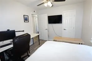 Interior room featuring light-toned walls, wood-finish flooring, a ceiling fan with integrated lighting, and multiple paneled doors