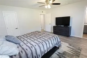 Spacious interior room featuring light-toned walls, wood-finish flooring, and a ceiling fan with integrated lighting