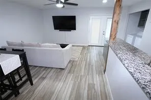 Open concept living area featuring wood-finish flooring and a ceiling fan with integrated lighting