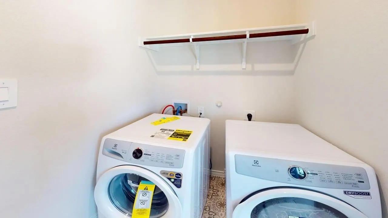 Dedicated laundry area featuring a patterned floor, wall-mounted shelving, and appliance hookups