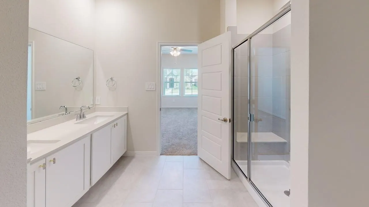 Dual vanity featuring white cabinetry, integrated sinks, chrome fixtures, and a large wall-mounted mirror