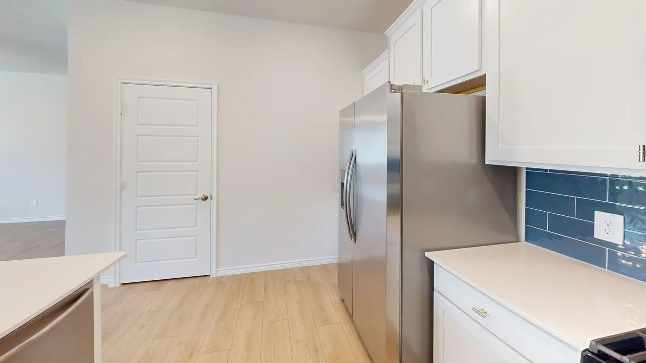 Contemporary kitchen featuring white cabinetry with brushed nickel hardware, light countertops, and a blue subway tile backsplash
