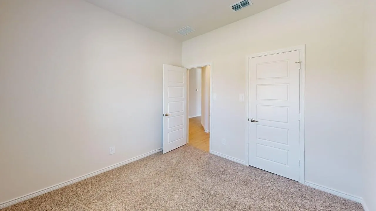 Room featuring neutral-toned carpeting, light-colored walls, and a white paneled door with a polished chrome knob
